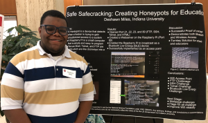 Student standing in front of his poster at the Summer Research Experiences Program